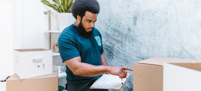 A man from packing services Philadelphia offers is taking the inventory of packed cardboard boxes.