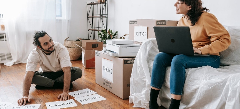 A couple is preparing labels for cardboard boxes.