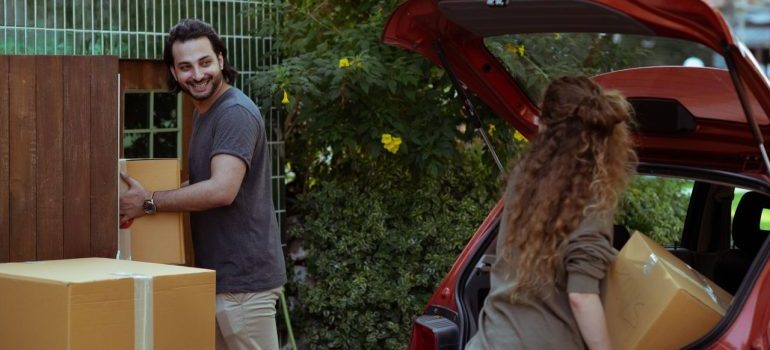 couple unpacking boxes from their car