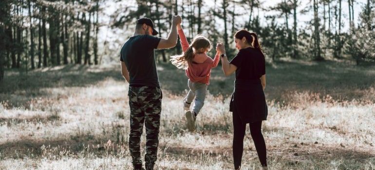 Happy family stroll through sunlit forest, capturing parent-child bond.