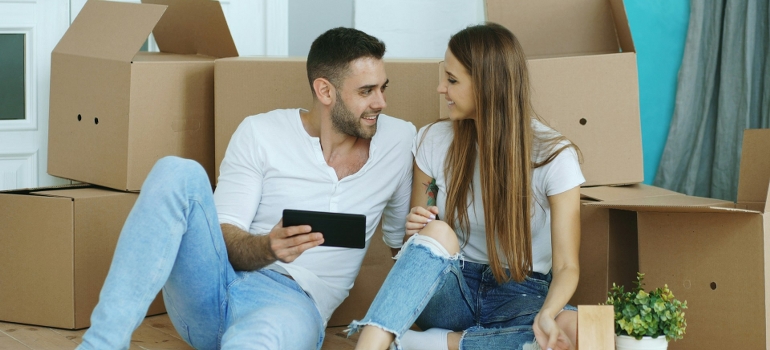 young couple sitting between moving boxes